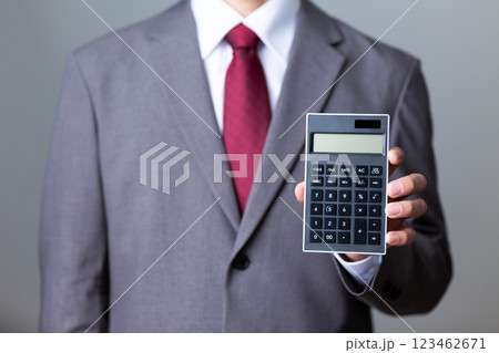 グレーのスーツを着て黒い電卓を持つミドル男性ビジネスマン グレーのスーツを着て黒い電卓を持つミドル男性ビジネスマン 123462671