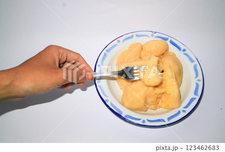An Asian woman's hand holding a fork picks up cassava tape on a plate An Asian woman's hand holding a fork picks up cassava tape on a plate 123462683