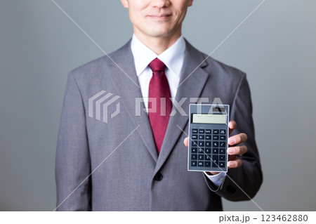 グレーのスーツを着て黒い電卓を持つミドル男性ビジネスマン 123462880