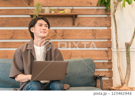 家のソファでくつろぎながらパソコンを使う若いアジア人男性 家のソファでくつろぎながらパソコンを使う若いアジア人男性 123462948