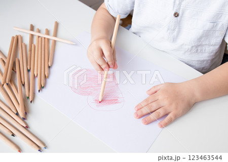Young caucasian child drawing heart with colored pencils on paper Young caucasian child drawing heart with colored pencils on paper 123463544