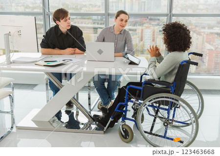 Teamwork brainstorm. Diverse multiracial colleagues woman in chair for people with disability working together. Group of people sitting in creative office discussing business. Young professional team 123463668