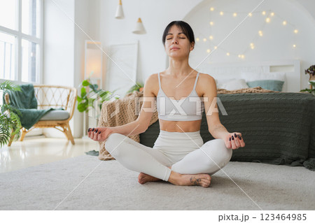 Yoga mindfulness meditation. Young healthy woman practicing yoga in living room at home. Woman sitting in lotus pose meditating smiling relaxing indoor. Girl doing breathing practice. Yoga at home Yoga mindfulness meditation. Young healthy woman practicing yoga in living room at home. Woman sitting in lotus pose meditating smiling relaxing indoor. Girl doing breathing practice. Yoga at home 123464985