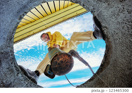 Bottom view of man immersing sewage pump into waste water of septic tank. Bottom view of man immersing sewage pump into waste water of septic tank. 123465300
