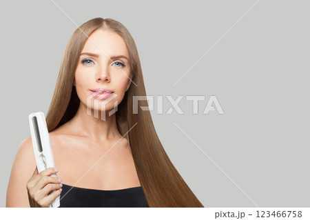 Posing fashion model with brown shiny straight haistyle portrait. Cute woman with straightening iron Posing fashion model with brown shiny straight haistyle portrait. Cute woman with straightening iron 123466758
