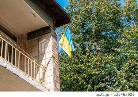 Ukrainian flag hangs on the facade of an old building. Blue yellow Ukrainian flag. 123468929