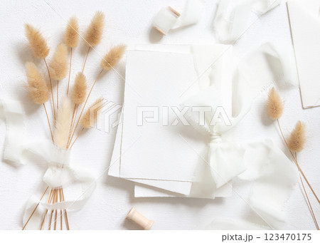Blank cards tied with a white silk ribbons near hare's tail grass top view on white, wedding mockup 123470175