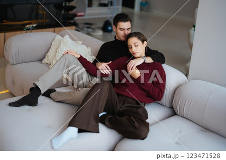 Couple relaxing together on a modern sofa in a cozy living room setting Couple relaxing together on a modern sofa in a cozy living room setting 123471528