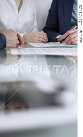 Unrecognizable business people are reviewing contract terms during a meeting while sitting at the glass table in office, vertical close up view. Copy space area 123471529
