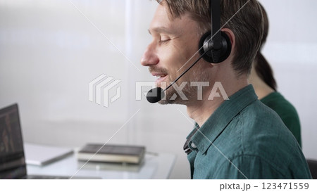 Focused male call center operator in green casual shirt is assisting clients online, providing customer support and answering inquiries. Call center concept Focused male call center operator in green casual shirt is assisting clients online, providing customer support and answering inquiries. Call center concept 123471559