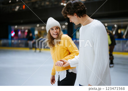 Couple enjoys ice skating together at a rink during winter evening 123471568