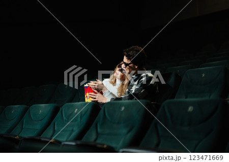 Couple enjoys movie time together while sharing popcorn in theater 123471669