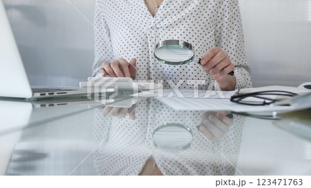 Businesswoman carefully reviewing financial reports with magnifying glass and calculator, conducting audit and analyzing data. Taxes, audit in business Businesswoman carefully reviewing financial reports with magnifying glass and calculator, conducting audit and analyzing data. Taxes, audit in business 123471763