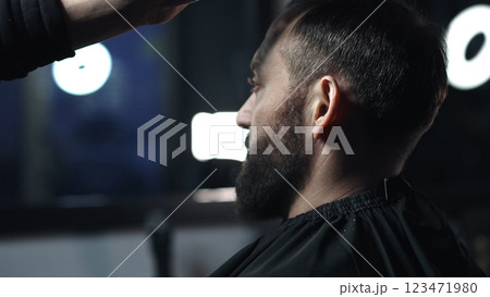 Skilled barber grooming client's hair with precision, working inside contemporary barbershop setting, preparing stylish haircut 123471980
