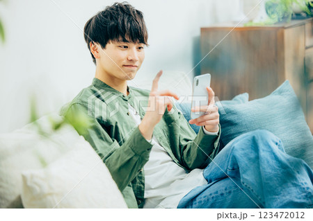 リビングでスマホを見る若い男性 リビングでスマホを見る若い男性 123472012