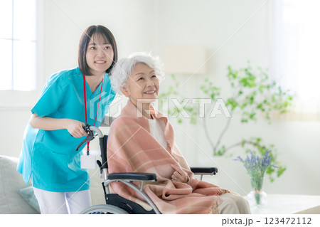 車椅子のシニアの女性と介護スタッフ 123472112