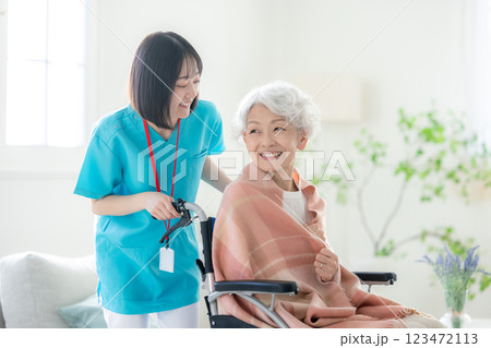 車椅子のシニアの女性と介護スタッフ 123472113