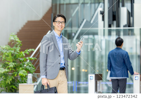 スマホを持つビジネスマン　改札の前 123472342