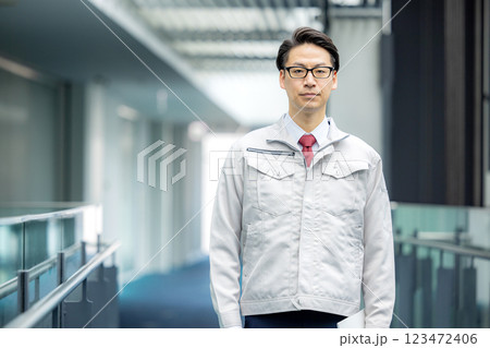 オフィスの廊下に立つ作業服の男性 オフィスの廊下に立つ作業服の男性 123472406