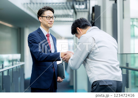 握手 作業着の男性とスーツの男性 握手 作業着の男性とスーツの男性 123472416