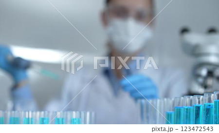 Laboratory tubes are in focus, closeup view. Female scientist researcher is using a micropipette at the background. Medicine and science concept Laboratory tubes are in focus, closeup view. Female scientist researcher is using a micropipette at the background. Medicine and science concept 123472543