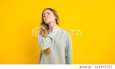 Young woman suffering from neck pain on yellow background Young woman suffering from neck pain on yellow background 123472722