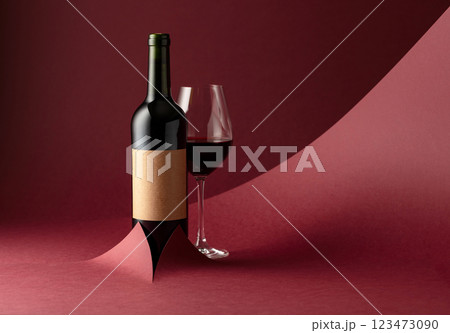 Bottle and glass of red wine on a red background. 123473090
