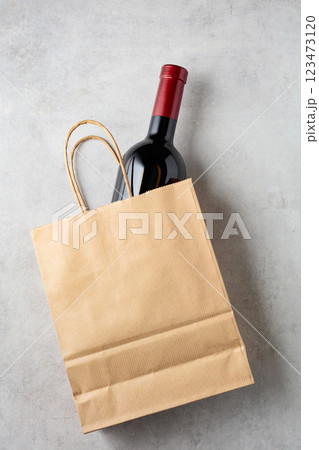 Bottle of red wine in a paper bag on a white stone background. 123473120