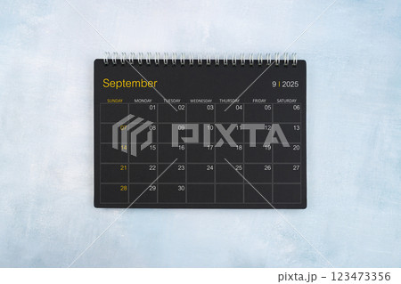 Blank calendar for September 2025, Black spiral desktop calendar on wooden background. 123473356