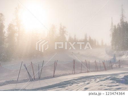 Sunlight filtering through fog on a snowy ski slope at a winter resort in the mountains during early morning hours 123474364
