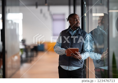 A confident, mature businessman in his 40s-50s using a tablet in a modern office. He is engaged in digital finance management, leveraging technology and artificial intelligence for investment 123476713