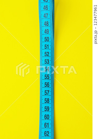 Blue tape measure diet concept on yellow background with copyspace Blue tape measure diet concept on yellow background with copyspace 123477961
