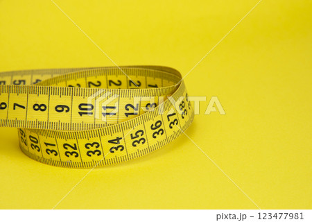 Yellow tape measure diet concept on yellow background with copyspace 123477981