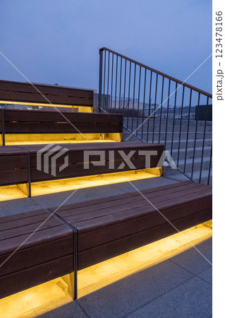 Wooden step and seating with lighting underneath, with metal handrail on the side 123478166