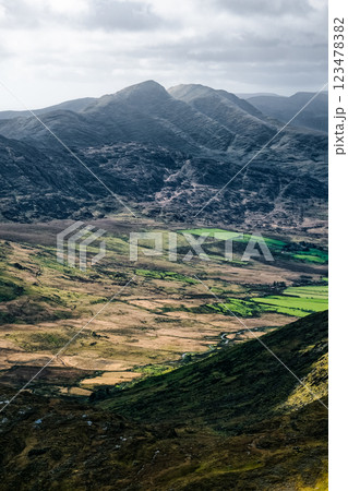 Stunning view of Carrauntoohil walkway with hills and lush green fields in Ireland under a dramatic sky. 123478382