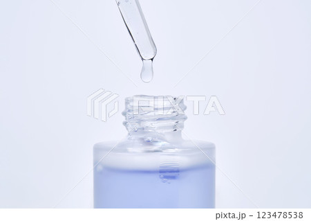 The blue serum drips from the dropper into the bottle. The blue serum drips from the dropper into the bottle. 123478538