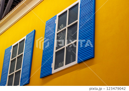 A bright yellow building featuring blue shutters adorning the windows A bright yellow building featuring blue shutters adorning the windows 123479042