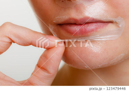 Woman removing facial peel off mask closeup Woman removing facial peel off mask closeup 123479446