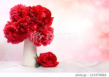Beautiful burgundy live peonies in elegant vase, gift for beloved, abstract flower arrangement for holiday card. Design template and screen background. Spring greeting concept Beautiful burgundy live peonies in elegant vase, gift for beloved, abstract flower arrangement for holiday card. Design template and screen background. Spring greeting concept 123479868