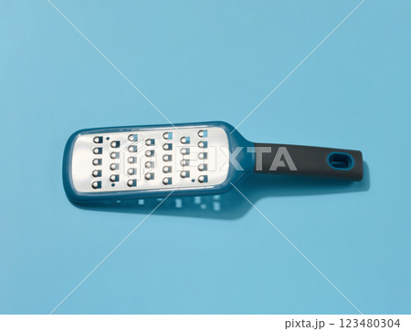 Metal vegetable grater on a blue background Metal vegetable grater on a blue background 123480304