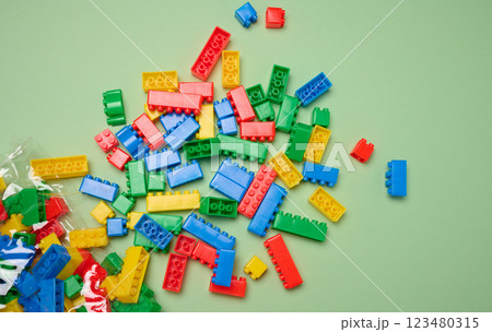 Scattered plastic multi-colored parts of children's construction set on green background, top view Scattered plastic multi-colored parts of children's construction set on green background, top view 123480315