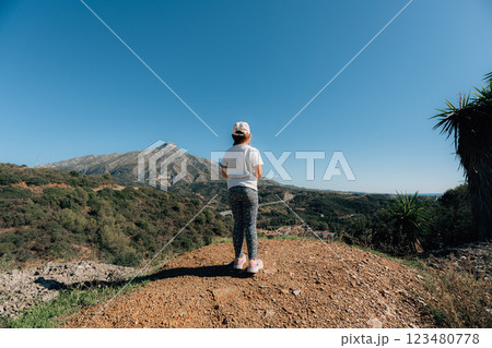 Young caucasian girl enjoying scenic mountain landscape under blue sky, slow living off grid free 123480778