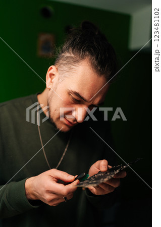 Vertical portrait of computer technician carefully cleaning motherboard components with small brush, focusing on precision and hardware maintenance, close-up. Concept of service and cleaning computer. 123481102