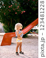 Little girl in sunglasses stands near a children slide. High quality photo 123481228