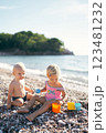 Little boy and girl with toy molds on a pebble beach. High quality photo 123481232