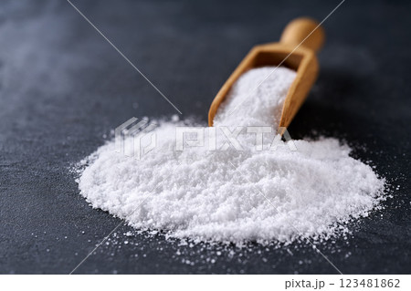 salt crystals in a small wooden scoop on a black stone table, selective focus. salt crystals in a small wooden scoop on a black stone table, selective focus. 123481862