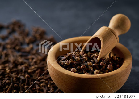 Wooden bowl with cloves spice on a black kitchen table, selective focus. 123481977