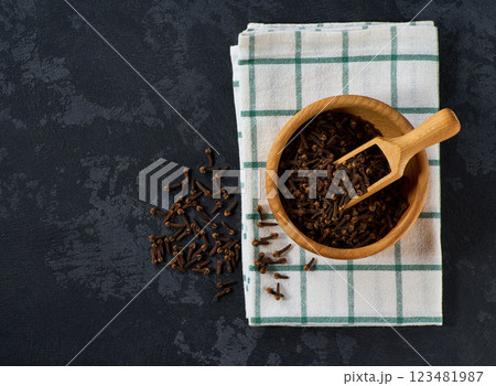 cloves in a wooden bowl on a black stone table, top view. 123481987