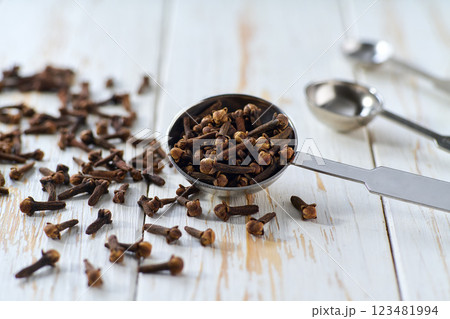 cloves spice in a measuring spoons on a white wooden table, selective focus. 123481994