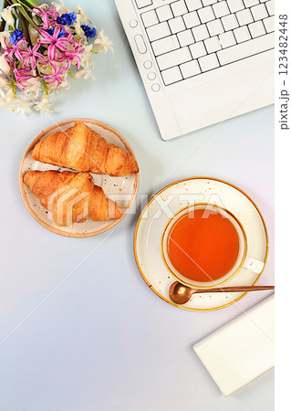 Modern feminine desk, home office. Computer, hyacinth flowers and a cup of tea, croissants on an elegant table, lifestyle concept, comfortable work from home, template for design, flat lay, Modern feminine desk, home office. Computer, hyacinth flowers and a cup of tea, croissants on an elegant table, lifestyle concept, comfortable work from home, template for design, flat lay, 123482448